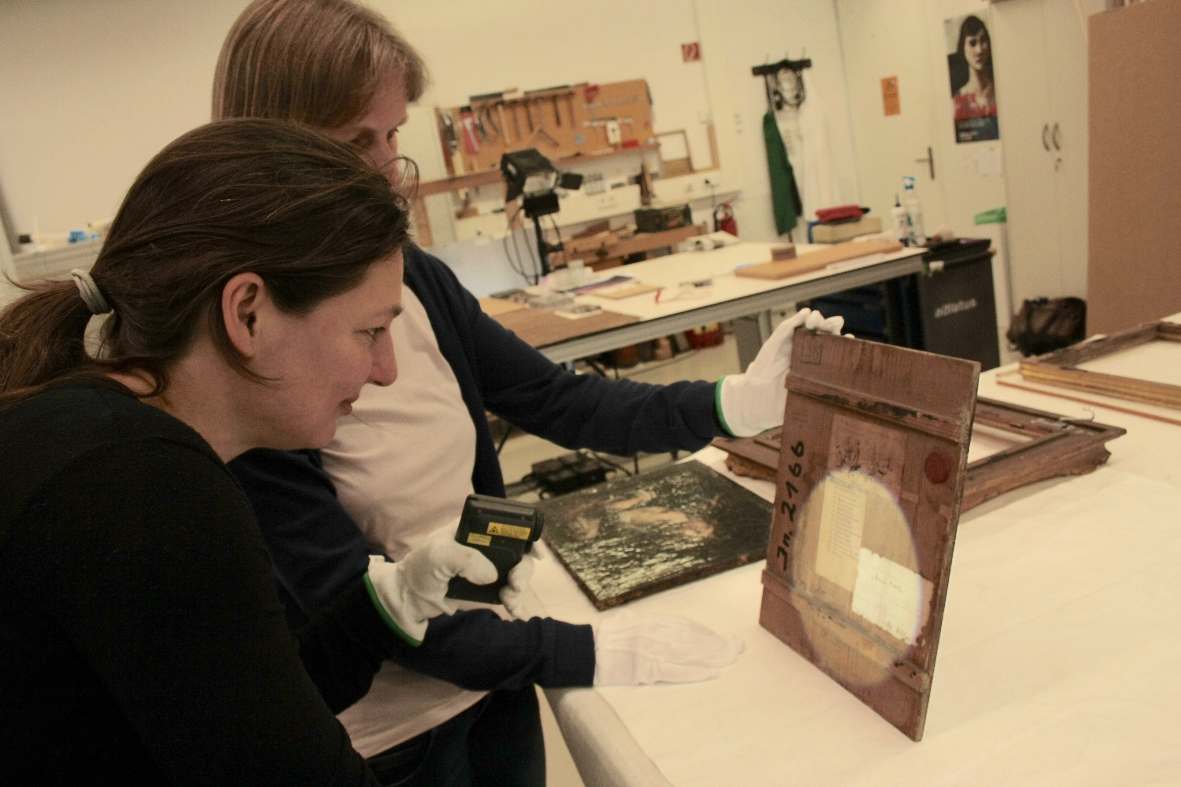 Kunsthistorikerin Birgit Brunk (vorn) und Restauratorin Antje Hake (im Hintergrund) begutachten ein Gemälde des „Milljöh“-Zeichners Wilhelm Busch. (Foto: ARTEFAKTE 2016)